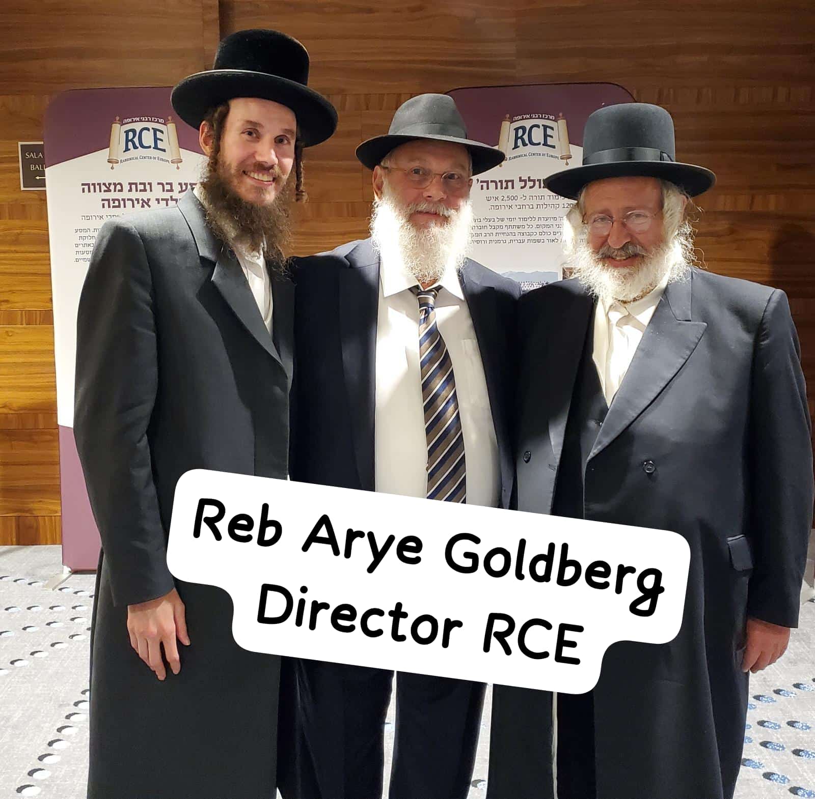 Reb Arye Goldberg, Director of the RCE, with two rabbanim beside the RCE banner at the convention